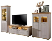 Wandkombination bestehend aus einem hohen Schrank, einem TV-Board und einem zweitürigen Schrank, alle in hellem Holz mit Glaseinsätzen und Beleuchtung, frontal betrachtet.