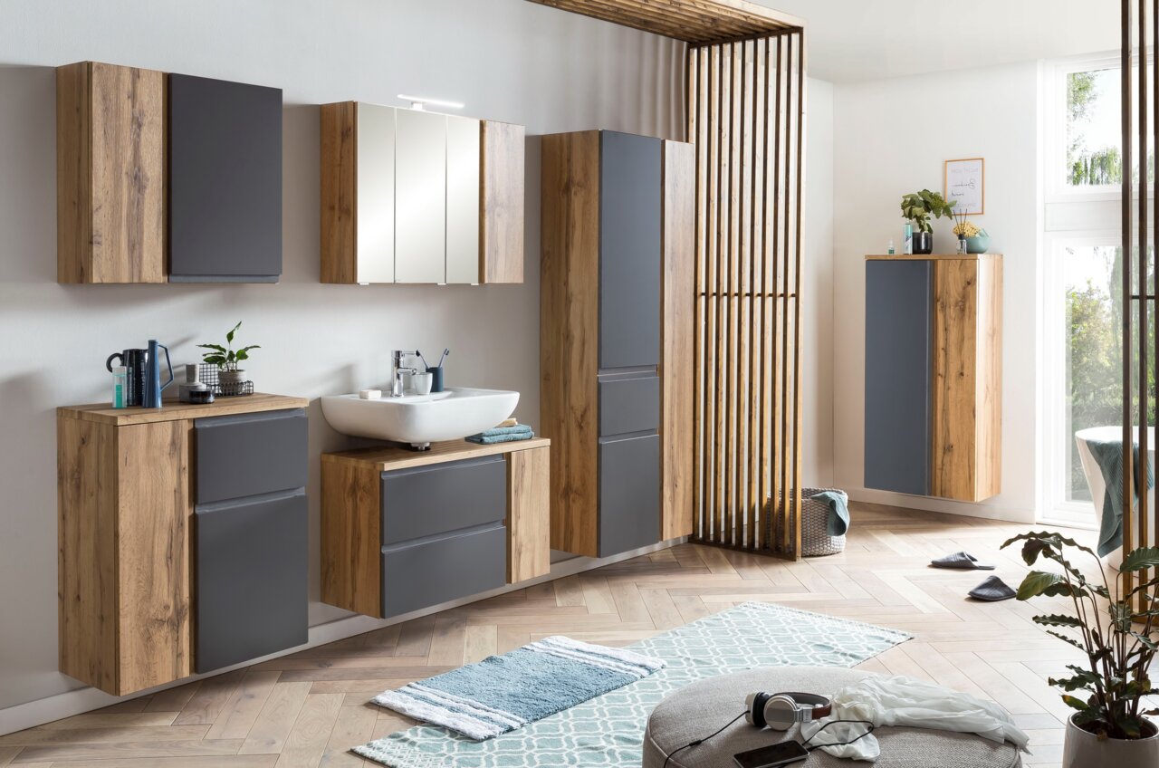 Moderne Badezimmermöbel in Holzoptik mit grauen Fronten, inklusive Hochschrank, aus seitlicher Perspektive fotografiert.
