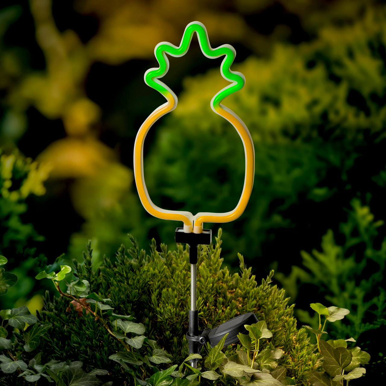 Lumineo Solar Stabbeleuchtung Solarbetriebene Stabbeleuchtung in Form einer Ananas, leuchtend in Gelb und Grün, in einem Garten platziert, seitliche Perspektive.