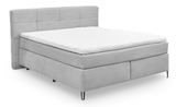 Graues Boxspringbett mit gestepptem Kopfteil, seitliche Perspektive