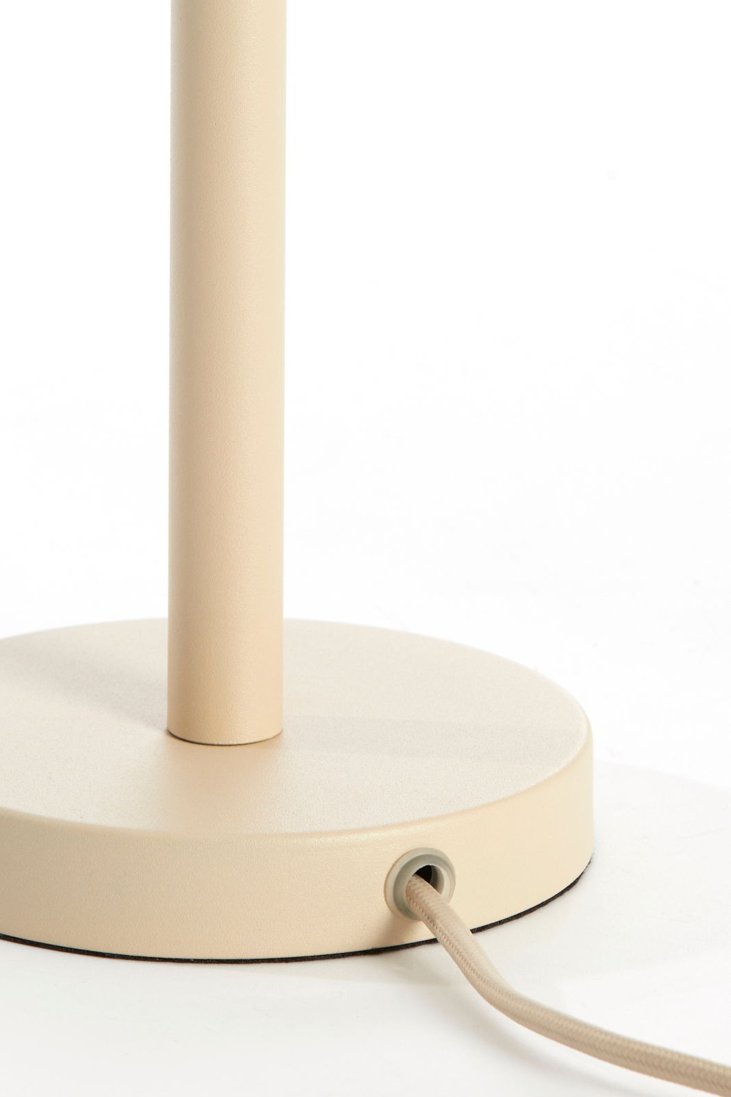 Nahaufnahme eines beigen Lampenfußes mit rundem Sockel und Kabel, seitliche Perspektive.