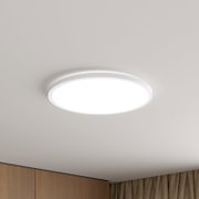 Runde, flache LED-Deckenleuchte in Weiß an der Zimmerdecke, eingeschaltet, in leichter Untersicht von unten fotografiert