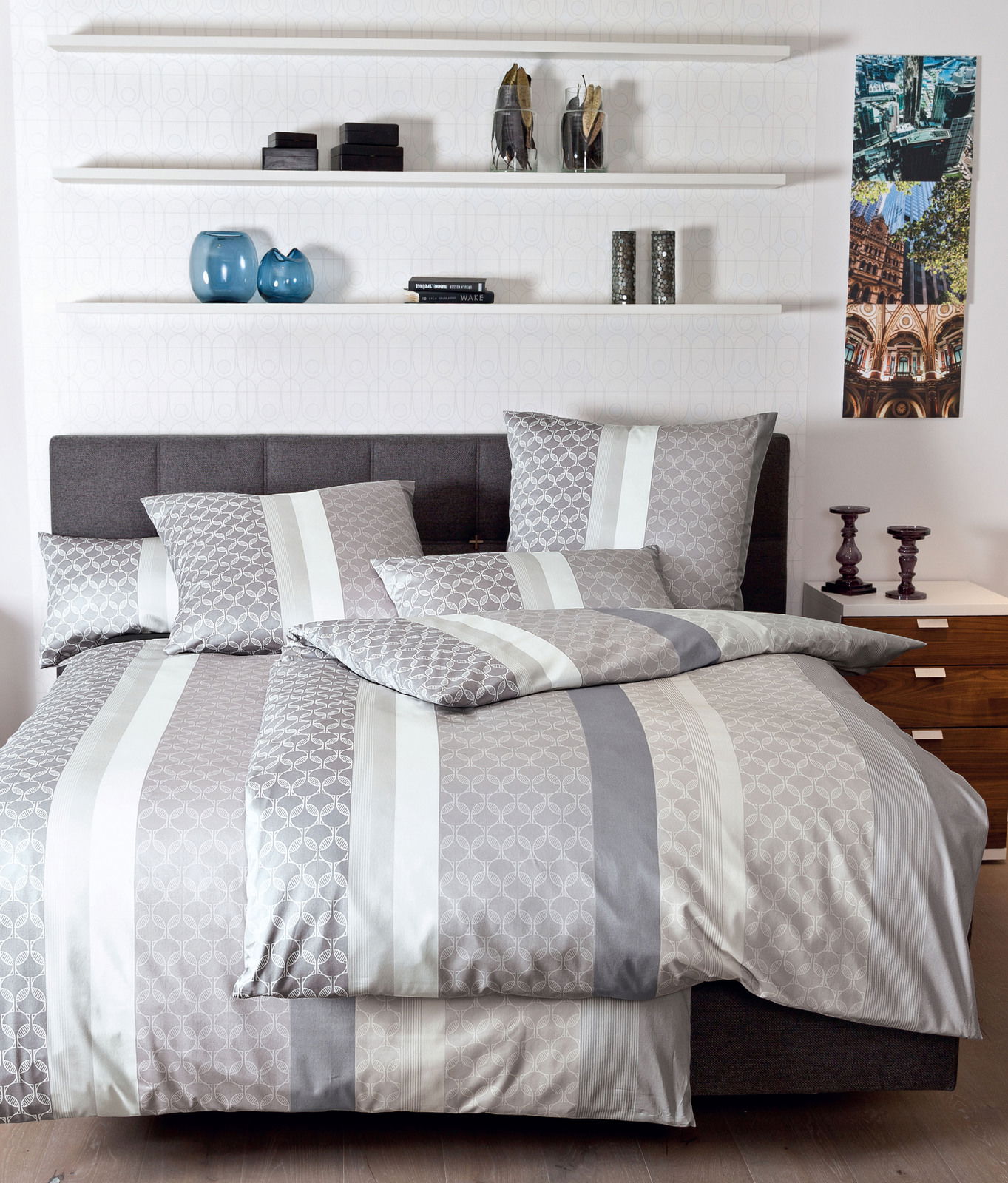 Bettwäsche-Set in Grau- und Weißtönen mit geometrischem Muster, auf einem Bett in einem modern eingerichteten Schlafzimmer, seitliche Perspektive