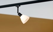 Basisspot in seitlicher Perspektive, montiert an einer Schiene, mit einem weißen Lampenschirm und schwarzem Halter.