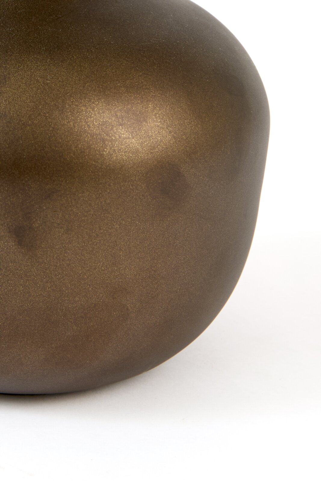 Close-up vanuit zijaanzicht van een afgerond decoratief object met een mat metallic bronskleurig oppervlak tegen een witte achtergrond