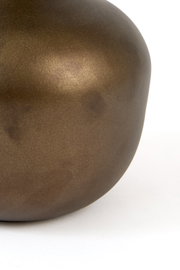 Close-up vanuit zijaanzicht van een afgerond decoratief object met een mat metallic bronskleurig oppervlak tegen een witte achtergrond