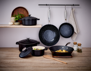 Küchenszene mit mehreren Kochutensilien, darunter eine Alu-Pfanne mit 24 cm Durchmesser, die an einer Stange hängt. Die Perspektive zeigt die Pfanne von vorne.