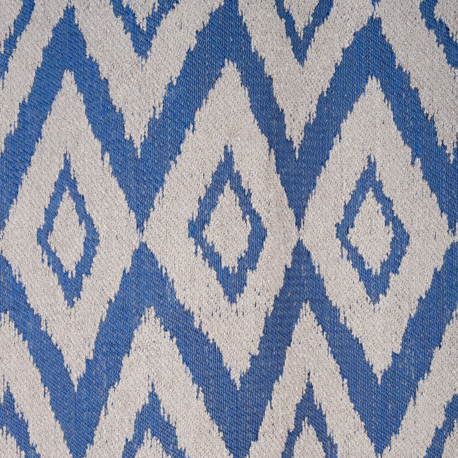 Nahaufnahme eines blauen und weißen geometrischen Musters auf einem Ösenschal, von oben betrachtet.