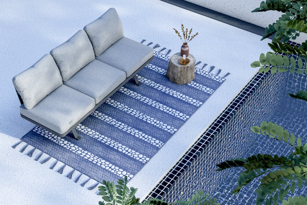 Driezits loungebank op een blauw tapijt naast een zwembad, gezien vanuit vogelperspectief.