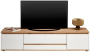 Frontansicht eines XL-TV-Lowboards mit Holzoberfläche, weißem Korpus, einem Fernseher, einer Lampe und Zeitschriften.