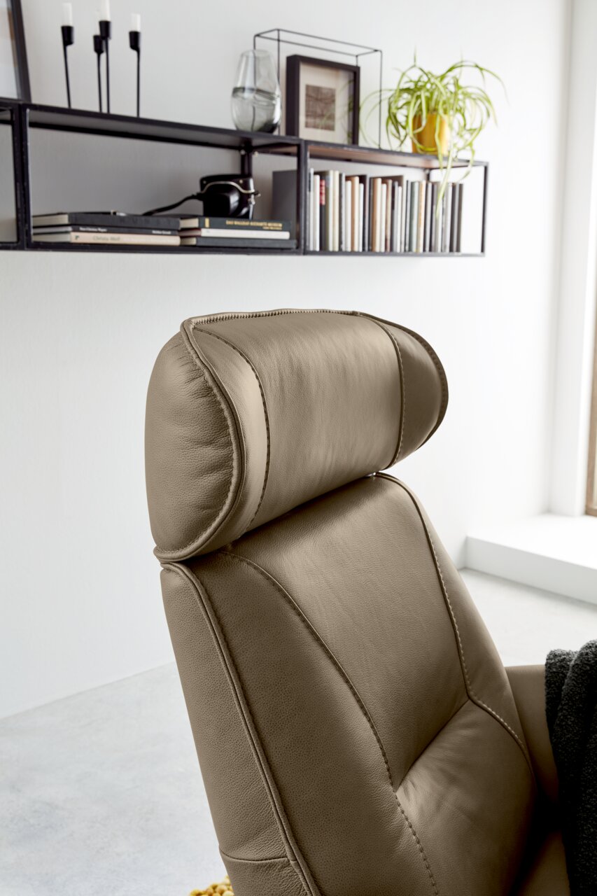 Nahaufnahme eines beigen Relaxsessels mit Kopfstütze, seitliche Perspektive.