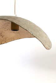 Nahaufnahme einer Hängeleuchte mit natürlicher, unregelmäßiger Oberfläche und gebogener Form, von unten betrachtet.