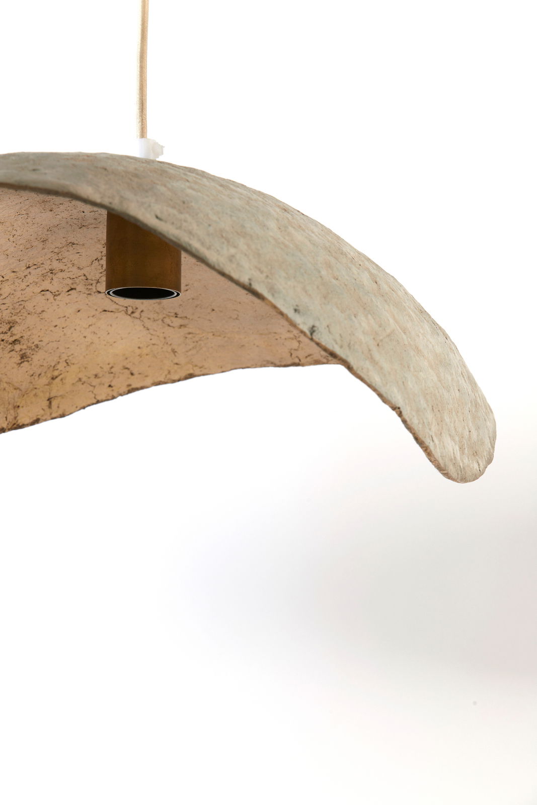 Nahaufnahme einer Hängeleuchte mit natürlicher, unregelmäßiger Oberfläche und gebogener Form, von unten betrachtet.