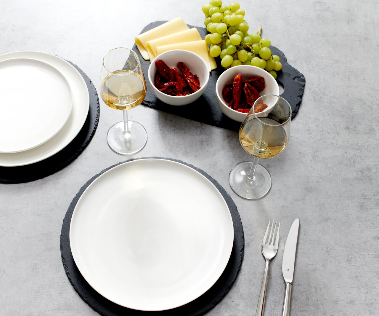 Dessertteller Skagen 21,5cm in einer Tischszene mit Wein, Trauben, Käse und getrockneten Tomaten, aus der Vogelperspektive.