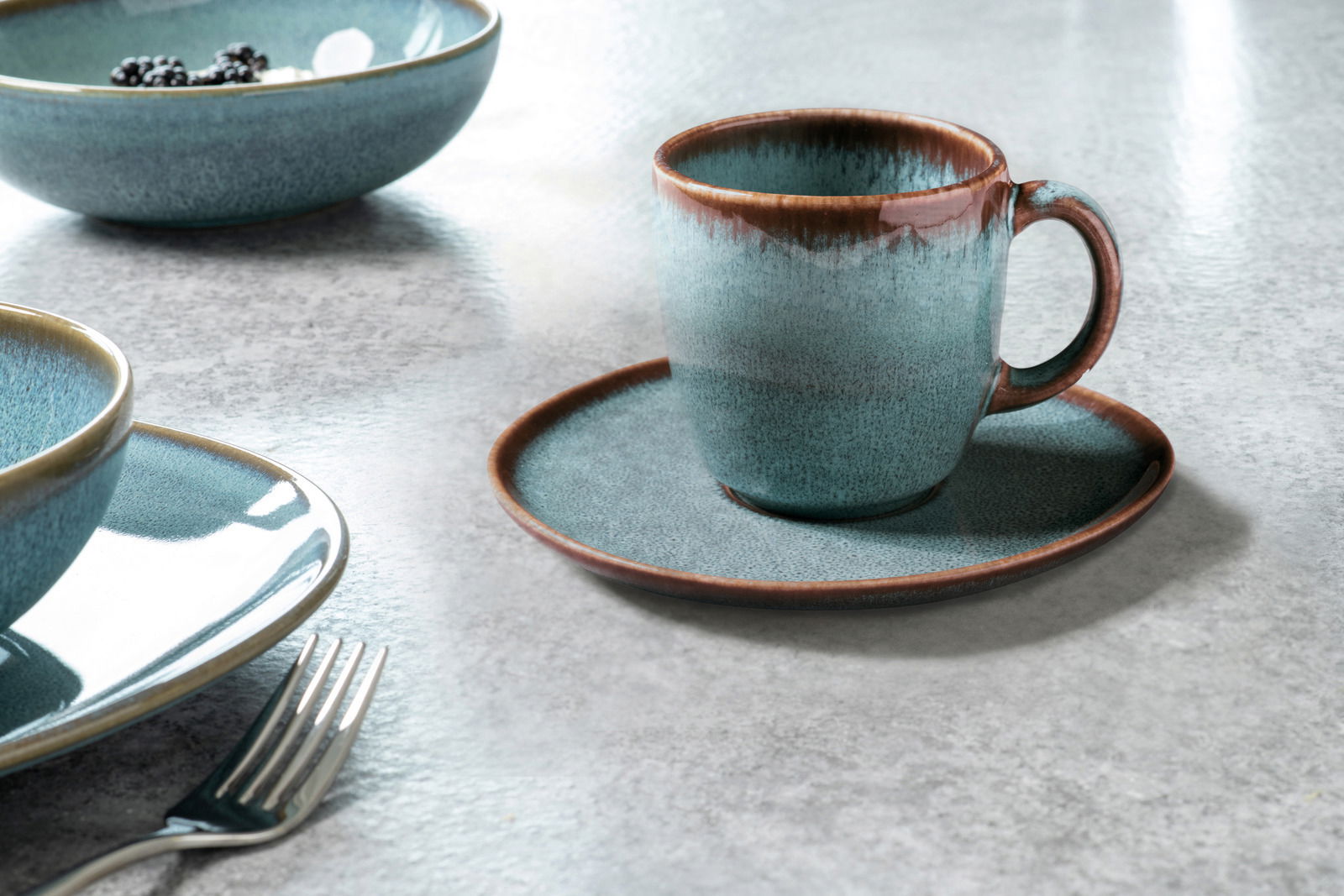 Kaffeetasse Lave 190ml in Türkis auf einem passenden Unterteller, seitliche Perspektive