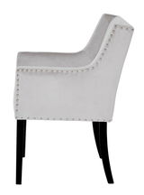 Seitenansicht eines eleganten, hellgrauen Stuhls mit Nietenverzierung und schwarzen Beinen.