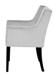 Seitenansicht eines eleganten, hellgrauen Stuhls mit Nietenverzierung und schwarzen Beinen.