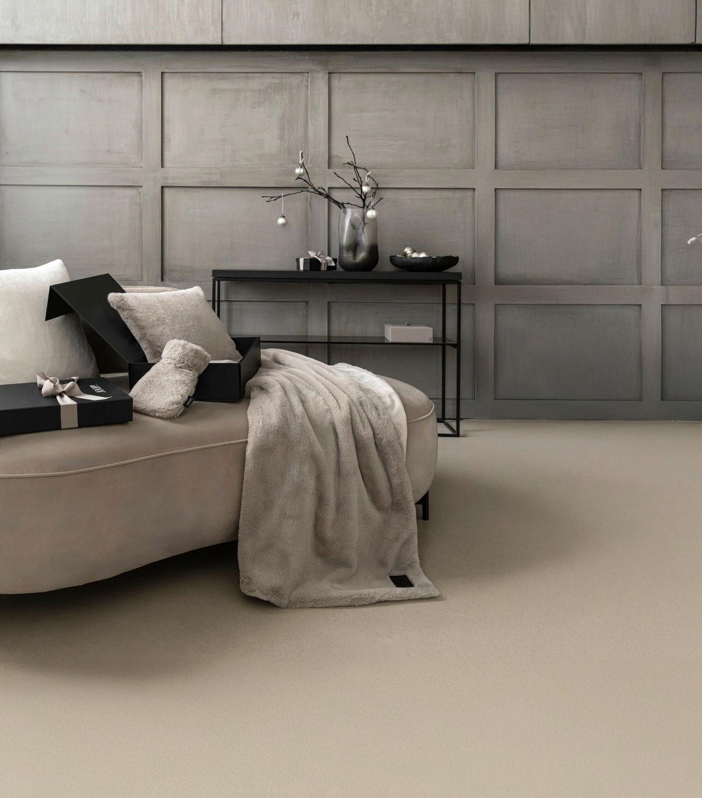 Elegantes Geschenkset mit weicher Decke und Kissen auf einem Sofa, seitliche Perspektive