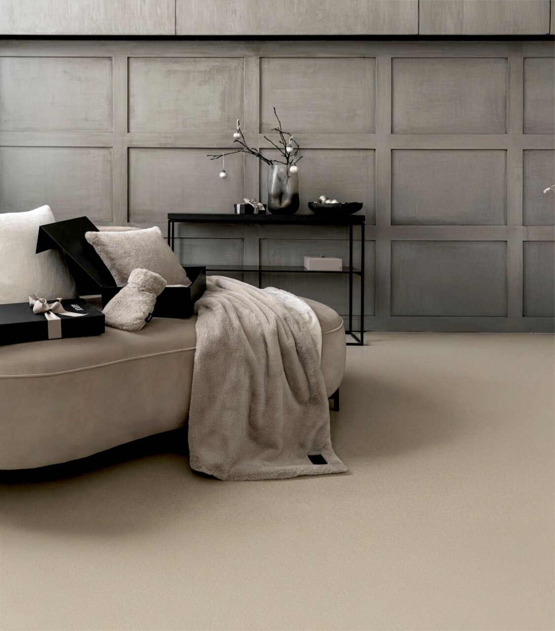 Elegantes Geschenkset mit weicher Decke und Kissen auf einem Sofa, seitliche Perspektive