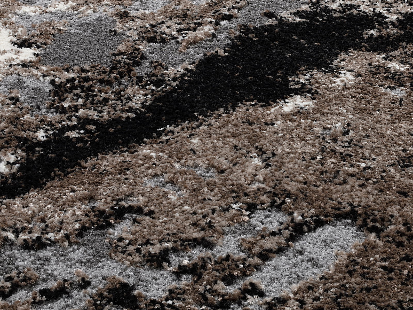 Nahaufnahme eines Designer-Teppichs mit abstraktem Muster in Braun-, Grau- und Schwarztönen, von oben betrachtet.