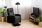 Modernes Wohnzimmer mit einem TV-Lowboard aus Holz und Metall, seitliche Perspektive. Daneben ein schwarzer Fernseher, eine Stehlampe und ein grauer Sessel. Pflanzen und Dekorationen ergänzen das gemütliche Ambiente.