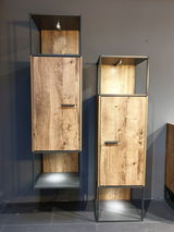 Zwei moderne Stand-/Hängeelemente aus Holz mit Metallrahmen, frontal fotografiert. Die Schränke haben eine natürliche Holzmaserung und integrierte Beleuchtung.