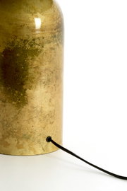 Detailaanzicht van de achterzijde van een cilindervormige lampvoet met verweerde goudkleurige afwerking en zwart snoer