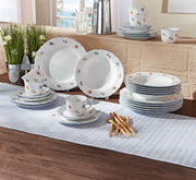 Kombiservice Sonate 30-tlg. mit floralem Muster, bestehend aus Tellern, Tassen und Untertassen, auf einem Tisch mit Tischdecke arrangiert, seitliche Perspektive.