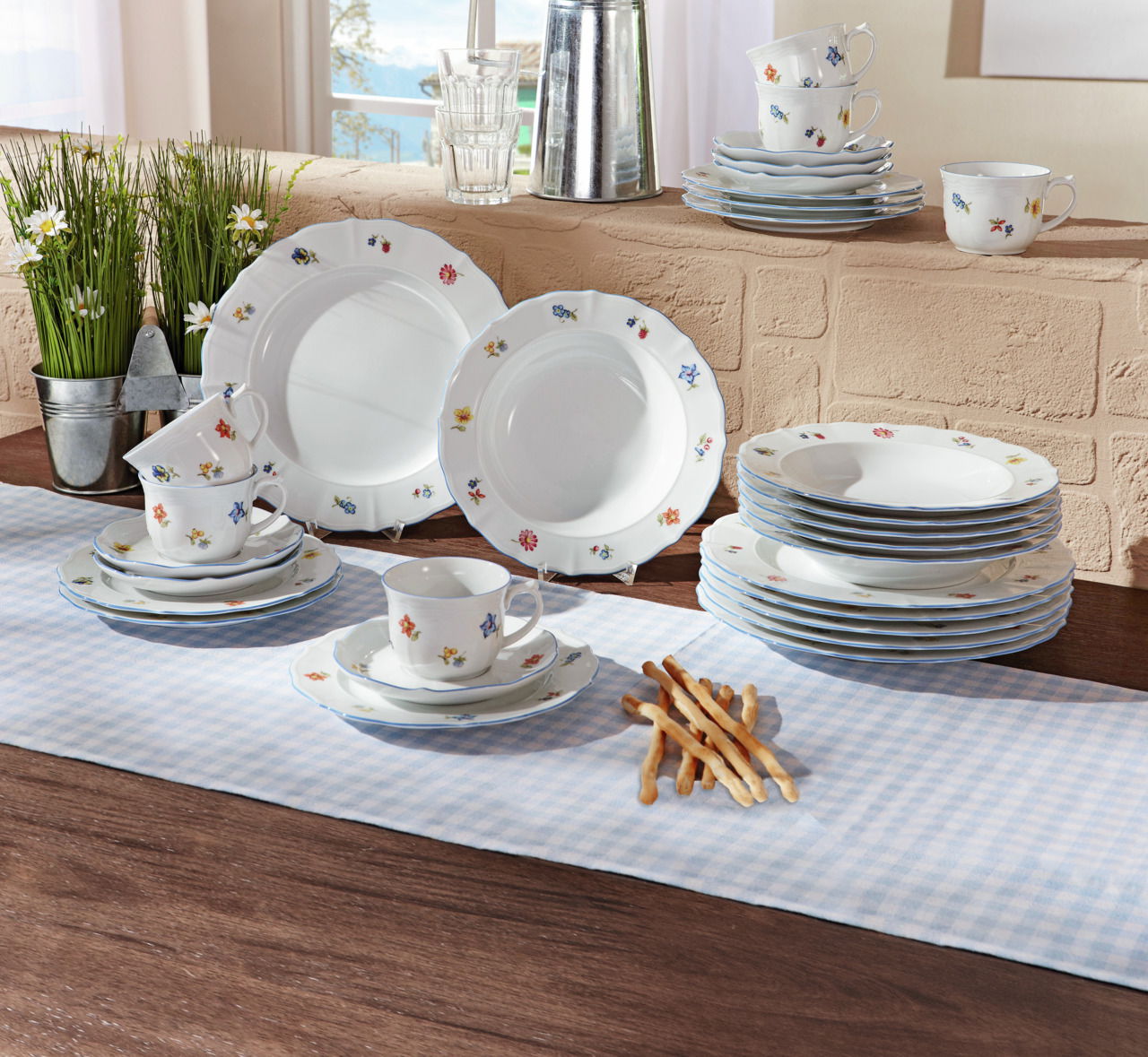 Kombiservice Sonate 30-tlg. mit floralem Muster, bestehend aus Tellern, Tassen und Untertassen, auf einem Tisch mit Tischdecke arrangiert, seitliche Perspektive.