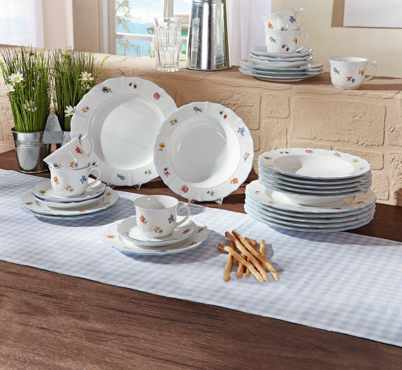 Kombiservice Sonate 30-tlg. mit floralem Muster, bestehend aus Tellern, Tassen und Untertassen, auf einem Tisch mit Tischdecke arrangiert, seitliche Perspektive.