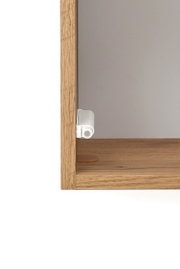 Close-up van een hangkast van hout met een wit scharnier, gezien vanaf de zijkant.