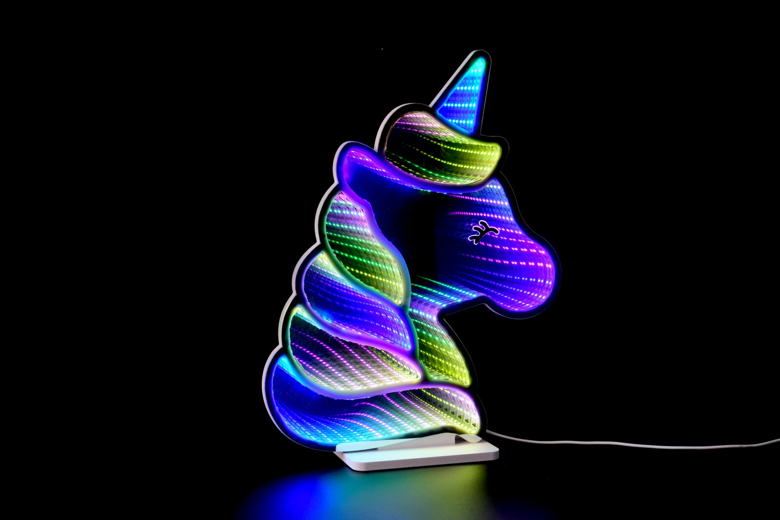 Bunte LED-Lampe in Einhornform mit regenbogenfarbenem Leuchteffekt auf weißem Sockel und Kabel vor schwarzem Hintergrund, seitliche Ansicht