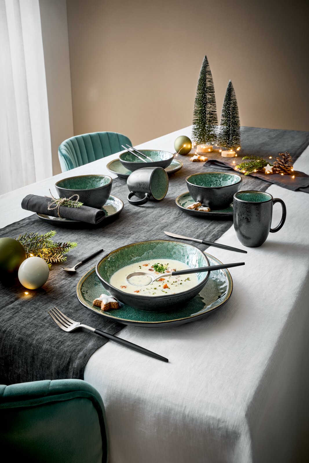 Elegantes Kombiservice für 10 Personen in stilvoller Tischdekoration mit grünen und schwarzen Schalen und Tassen, von schräg oben fotografiert.