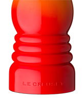 Nahaufnahme einer ofenroten Pfeffermühle von Le Creuset, seitliche Perspektive.