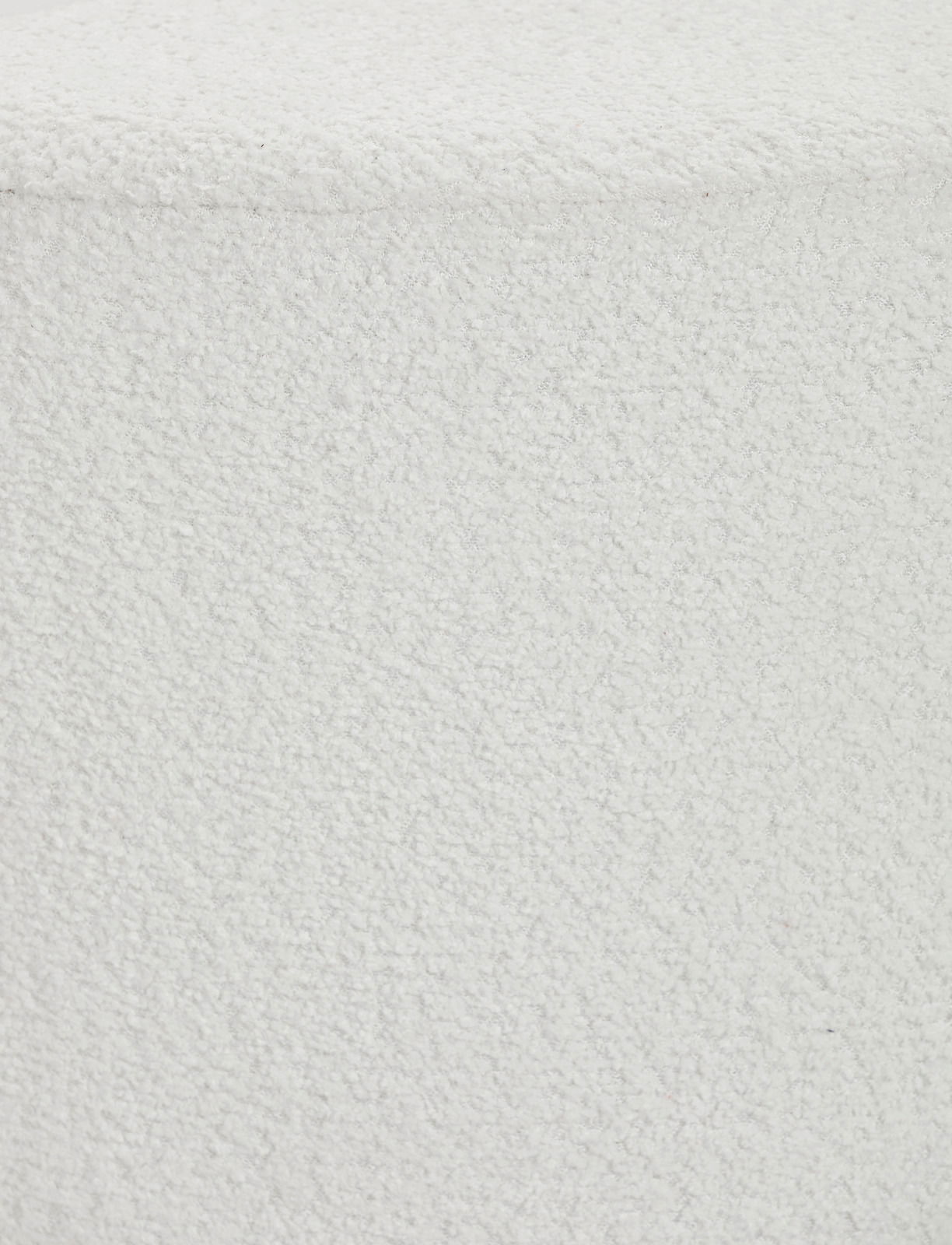 Nahaufnahme eines weißen Hockers mit texturierter Oberfläche, von oben betrachtet.