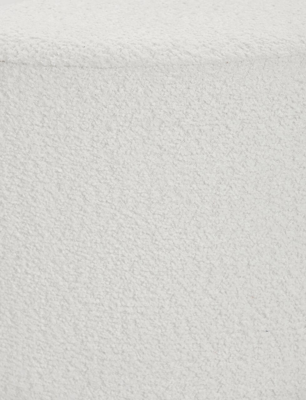 Nahaufnahme eines weißen Hockers mit texturierter Oberfläche, von oben betrachtet.