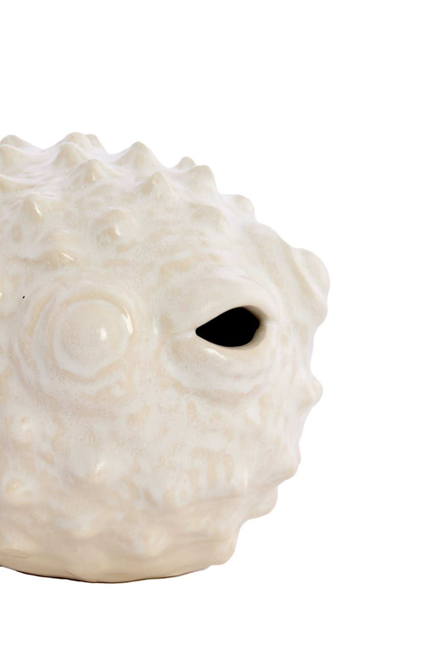 Nahaufnahme eines weißen, strukturierten Keramik-Ornaments in Form eines Kugelfisches, seitliche Perspektive