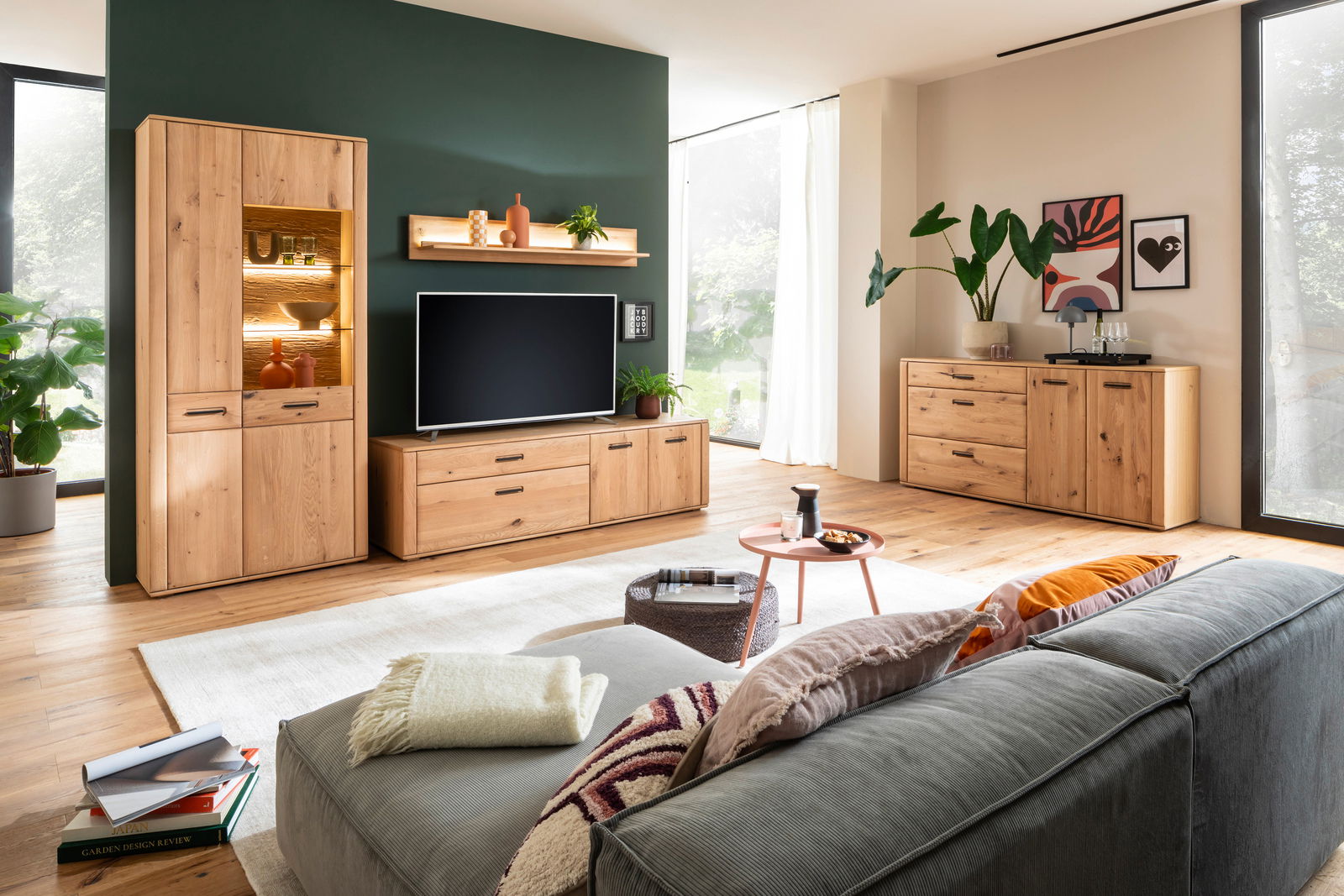 Moderne Wohnzimmermöbelkombination aus Holz mit Sideboard, TV-Schrank und Vitrine, aus der Perspektive eines gemütlichen Wohnzimmers mit Sofa im Vordergrund.