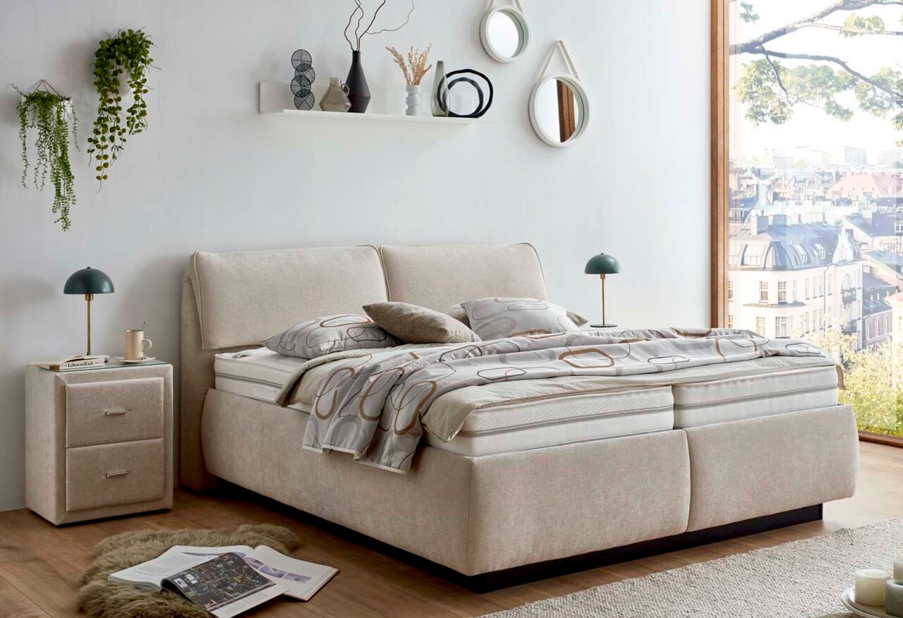 Modernes Polsterbett in einem stilvoll eingerichteten Schlafzimmer mit Blick auf die Stadt, seitliche Perspektive.