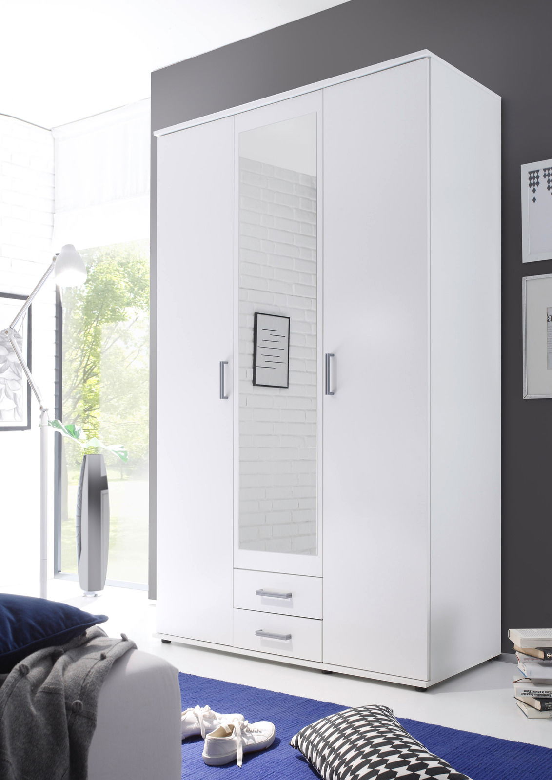 Moderner dreitüriger Drehtürenschrank in Weiß mit Spiegel in der Mitte, zwei Schubladen unten und silbernen Griffen, seitliche Perspektive