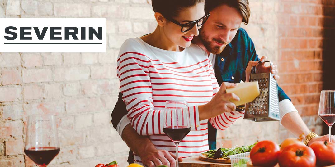 Ein Paar kocht gemeinsam, mit Wein, frischem Gemüse und Küchenutensilien der Marke Severin.