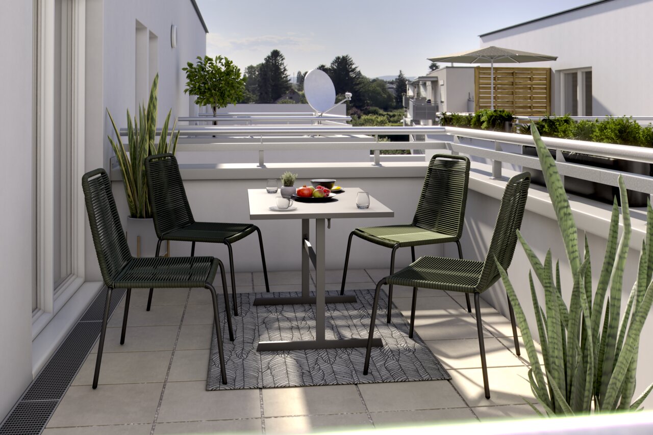 Vier grüne Stapelstühle um einen quadratischen Tisch auf einem Balkon, mit Pflanzen und einer Aussicht auf Bäume im Hintergrund, aus einer seitlichen Perspektive fotografiert.