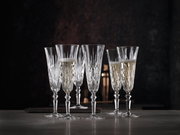 Sechs elegante Sektgläser aus Kristall mit feinem Schliff, teilweise gefüllt mit Sekt, auf einem Tisch vor dunklem Hintergrund, seitliche Perspektive.