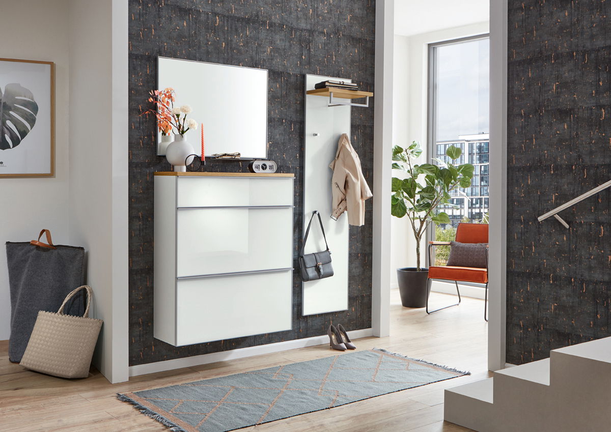 VOSS Garderobenpaneel schmal VORTINA Moderner Eingangsbereich mit weißem Hängeschuhschrank, großem Spiegel und schmalem Garderobenpaneel, seitliche Perspektive.