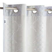 Gordijn met oogjes en bloemmotief in close-up, opgehangen aan een metalen stang