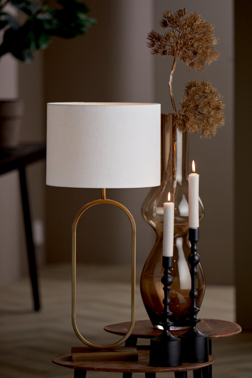 Moderner Lampenschirm in Zylinderform, frontal fotografiert, auf einem eleganten Tisch mit dekorativen Kerzen und einer Vase im Hintergrund.
