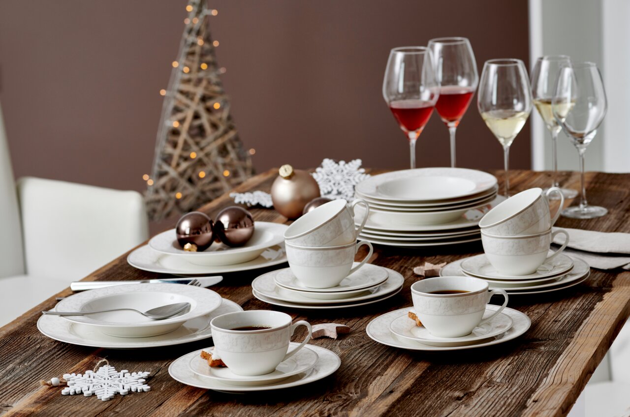 Ritzenhoff & Breker Kaffeetasse ISABELLA beige Elegantes Kaffeeservice Isabella auf einem rustikalen Holztisch, mit Tassen, Untertassen und Tellern in festlicher Atmosphäre, seitliche Perspektive.