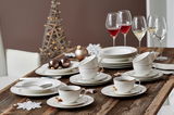 Elegantes Kaffeeservice Isabella auf einem rustikalen Holztisch, mit Tassen, Untertassen und Tellern in festlicher Atmosphäre, seitliche Perspektive.