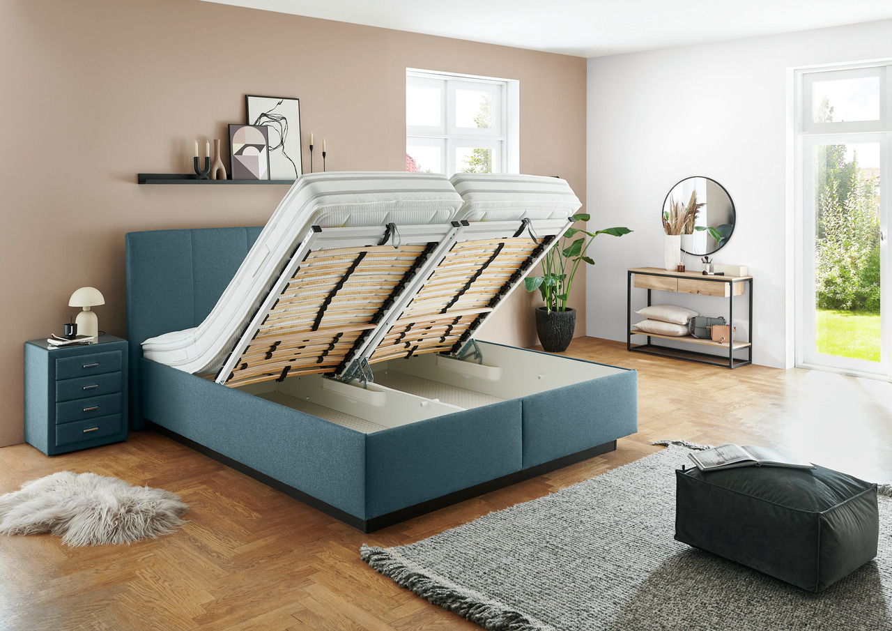 Modernes Polsterbett in einem stilvollen Schlafzimmer, mit hochgeklappten Lattenrosten für zusätzlichen Stauraum, aus einer seitlichen Perspektive fotografiert.