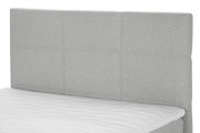 Graues Boxspringbett mit gestepptem Kopfteil, seitliche Perspektive